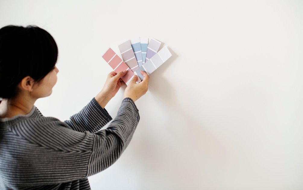Perempuan sedang tips memilih warna cat dinding dari lembar color swatch untuk rumah modern tropis