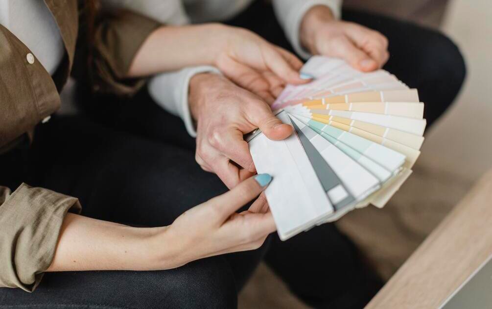 Pasangan memilih warna cat rumah minimalis menggunakan palet warna saat konsultasi desain interior