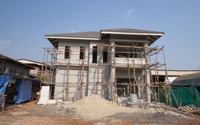 Rumah dua lantai dalam tahap konstruksi dengan scaffolding bambu, ilustrasi pentingnya cara memilih jasa arsitek rumah sebelum pembangunan