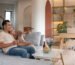 Pasangan duduk santai di sofa ruang tamu dengan ukuran ruang tamu yang nyaman dan fungsional