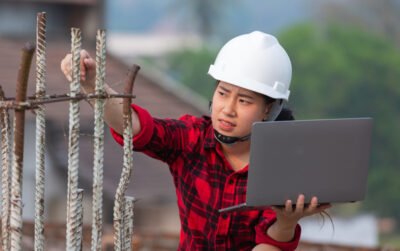 Insinyur muda terlihat bingung melihat laptop di lokasi konstruksi rumah, ilustrasi konsekuensi salah dalam cara memilih jasa arsitek rumah