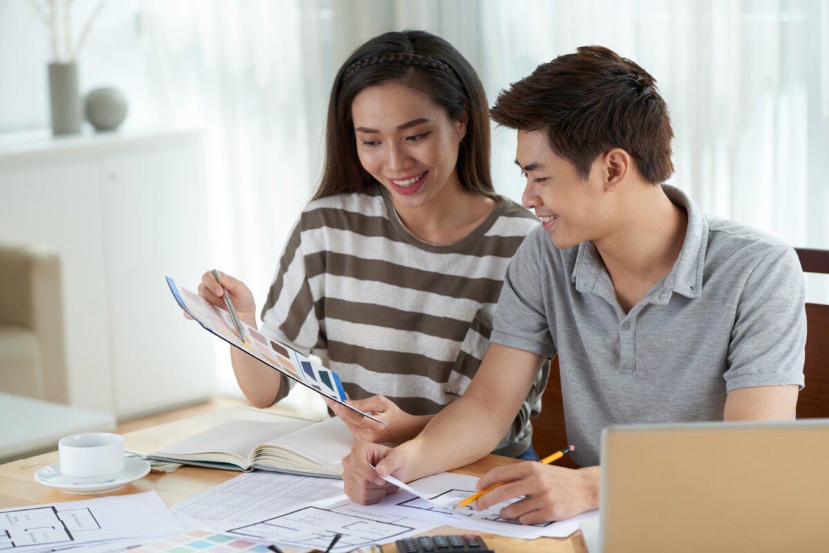 Pasangan muda mendiskusikan anggaran dan harga jasa arsitek per meter dengan denah rumah