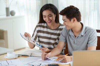 Pasangan muda mendiskusikan anggaran dan harga jasa arsitek per meter dengan denah rumah