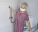 Lansia perempuan sedang memegang handrail di kamar mandi lansia yang dirancang aman untuk mengurangi risiko terpeleset