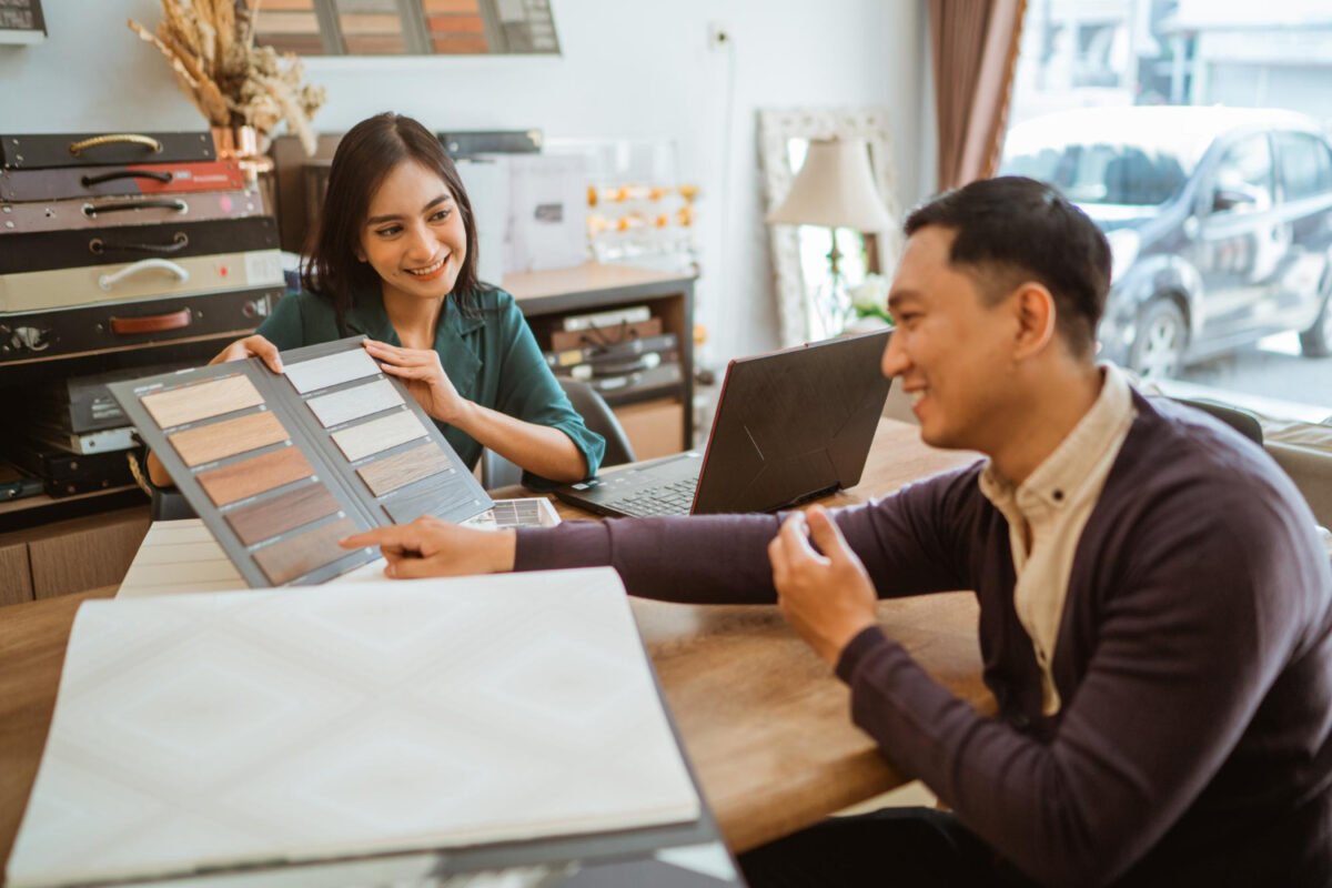 Desainer interior menjelaskan harga jasa desain interior per meter kepada klien menggunakan sampel material