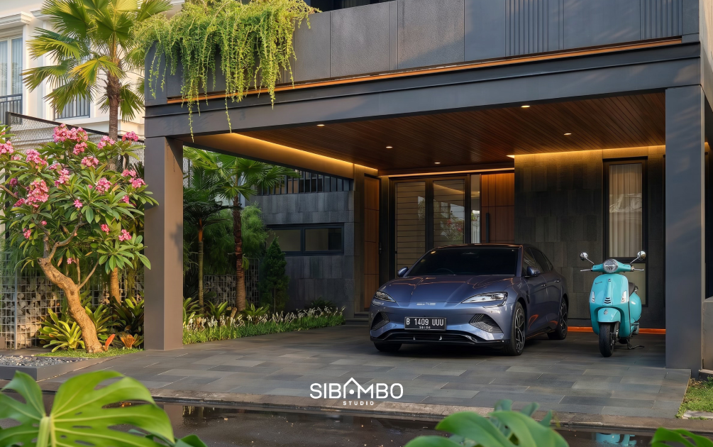 Area carport Aureva House dengan plafon kayu, tanaman menjuntai, dan dinding batu pada rumah modern tropis