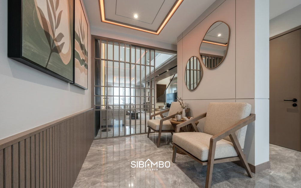 Ruang penerima tamu Elefate House dengan kursi kayu, cermin bulat, dan sekat kaca grid bergaya modern kontemporer